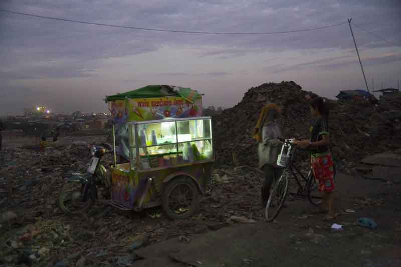 Nigel Dickinson: Fast-food mobile vendor selling snacks and drinks to a child worker, at dusk, at the edge of Smokey Mountain, 2007, mat archival prints, 40cm x 60cm